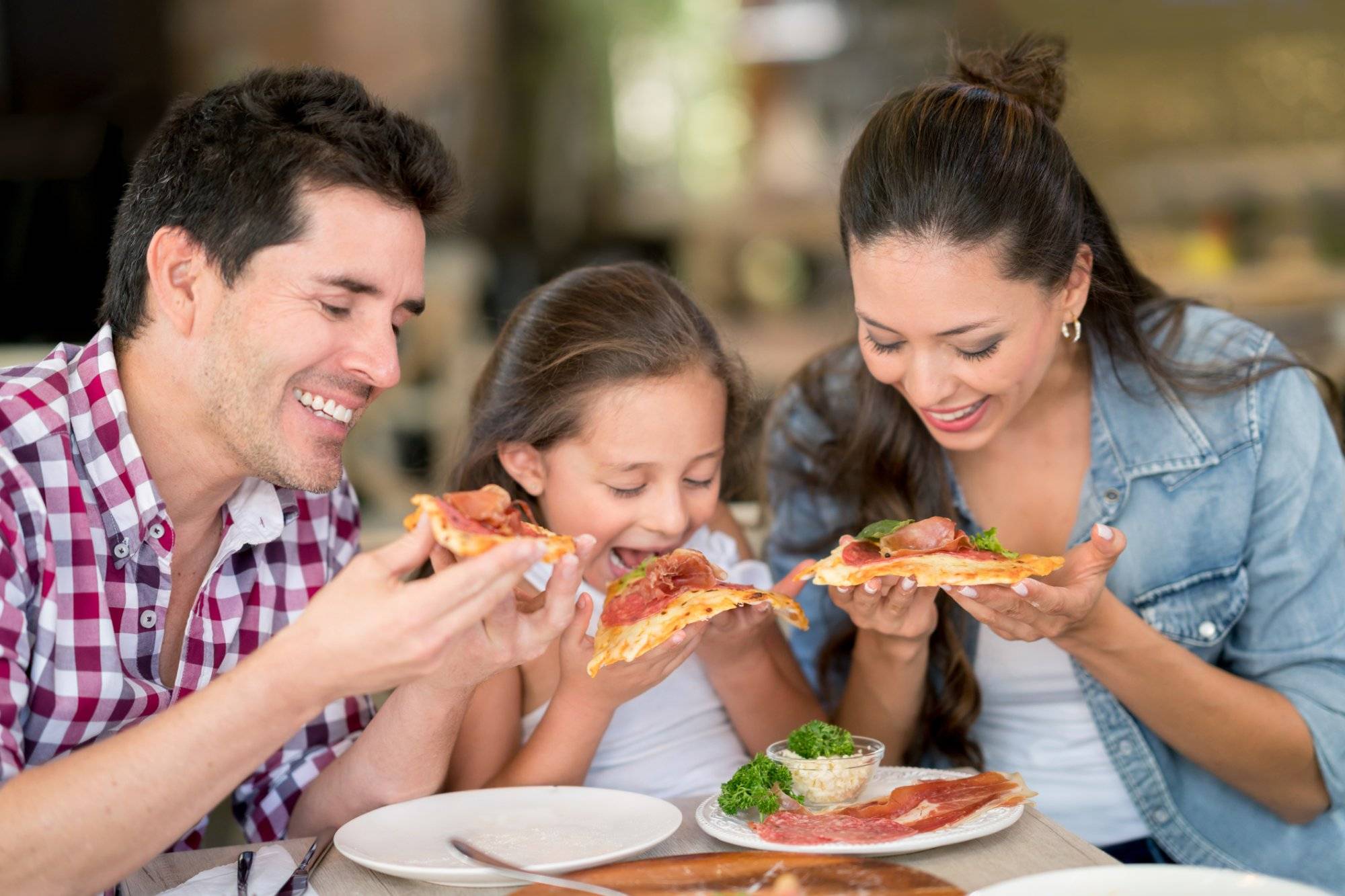 Happy family eating pizza at a restaurant Happy family eating pizza at a restaurant