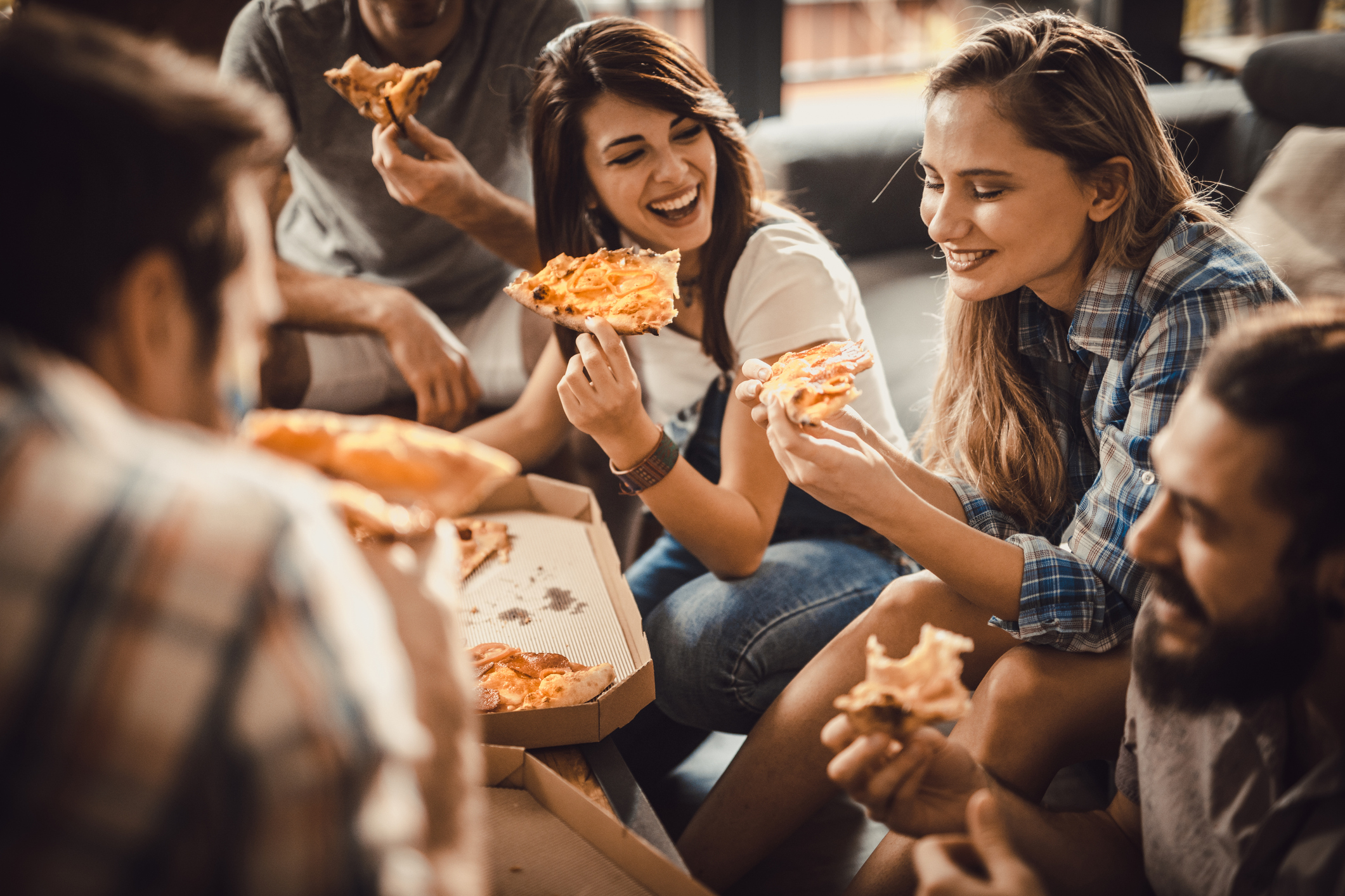 Young happy friends having fun while eating pizza at home.