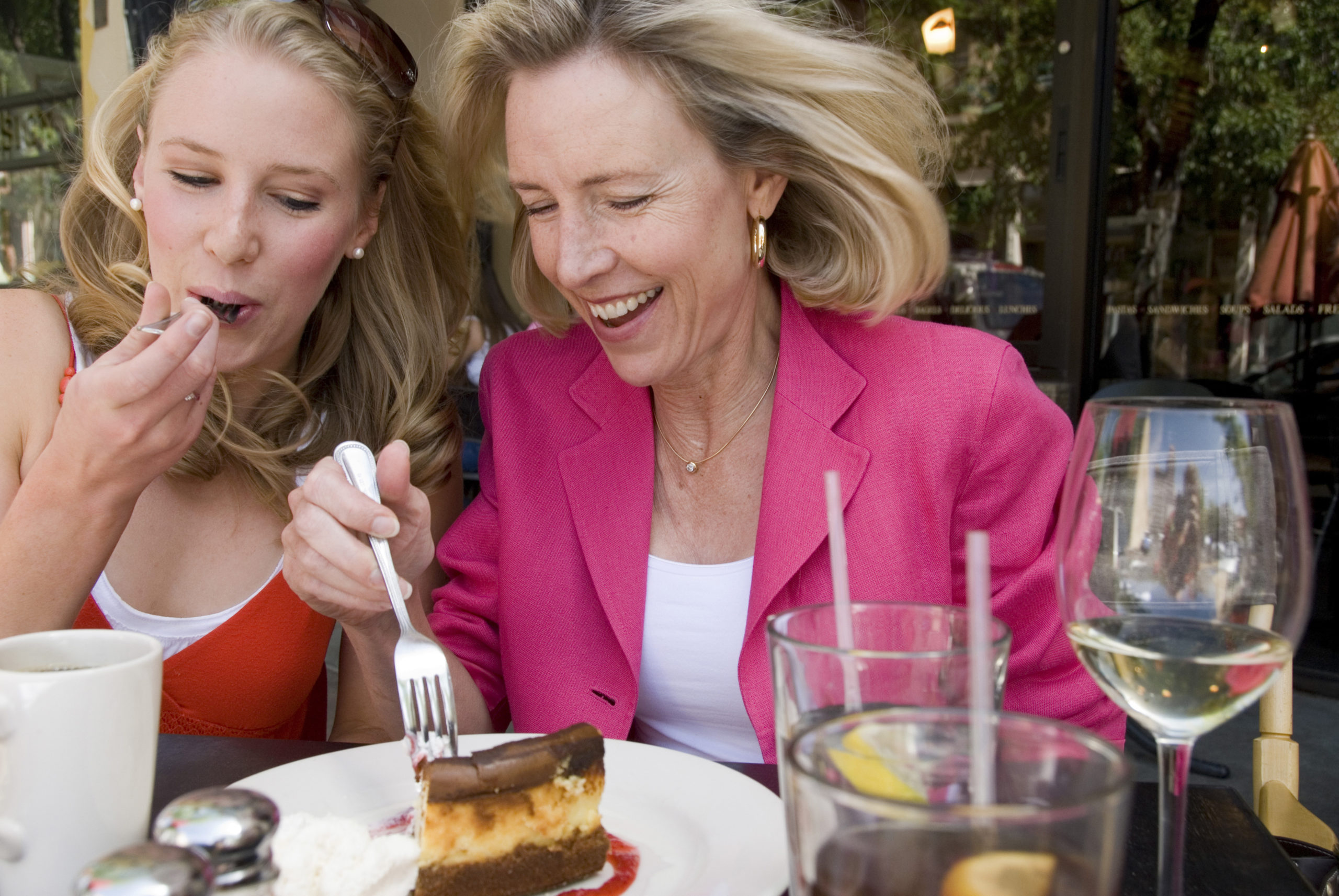 Mature woman sharing slice of cheesecake with her daughter