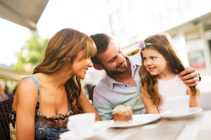 Young loving family having fun in a cafe eating cake.