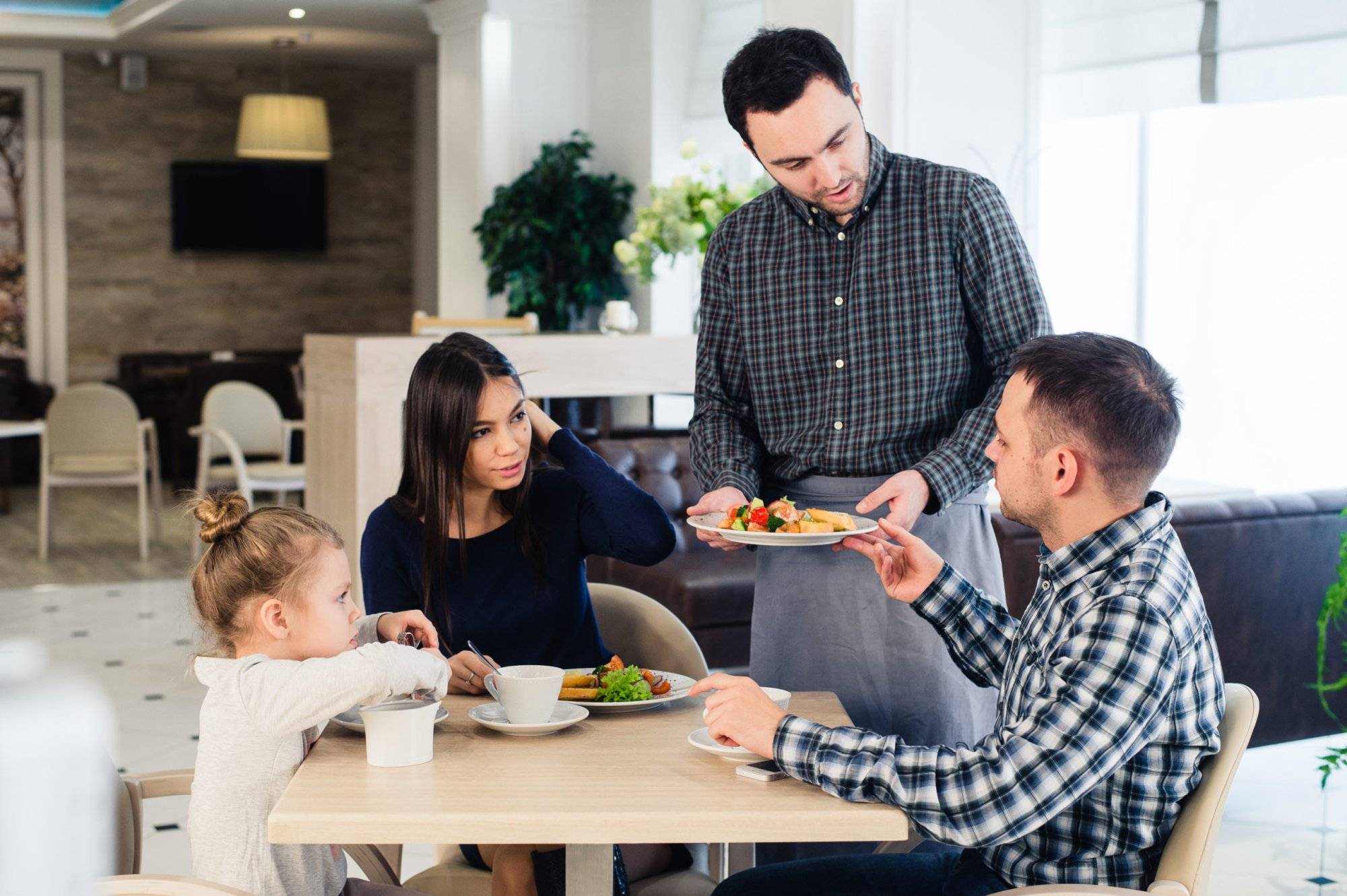 waiter-serving-family-in-a-restaurant-and-PXFJ3BY